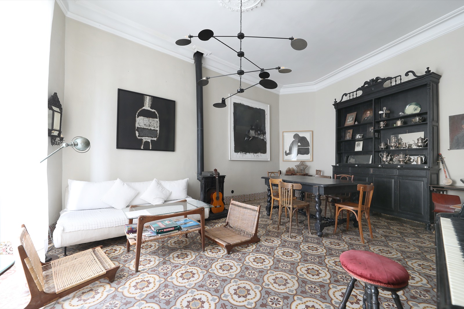 Le grand salon de Mimi Calpe &mdash; canapé blanc, carreaux de ciment à motifs et buffet noir chargé d&rsquo;argenterie
