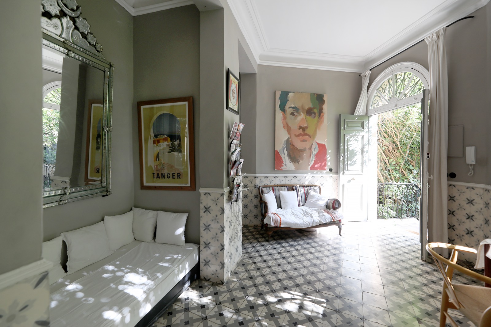 Un salon clair de la villa sous sa fenêtre en arc — canapés blancs, œuvres au mur, carreaux de ciment