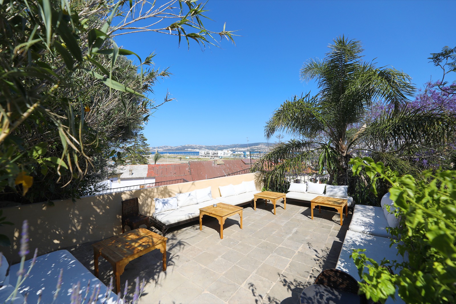 Une terrasse du jardin, transats et coin salon face à la baie de Tanger