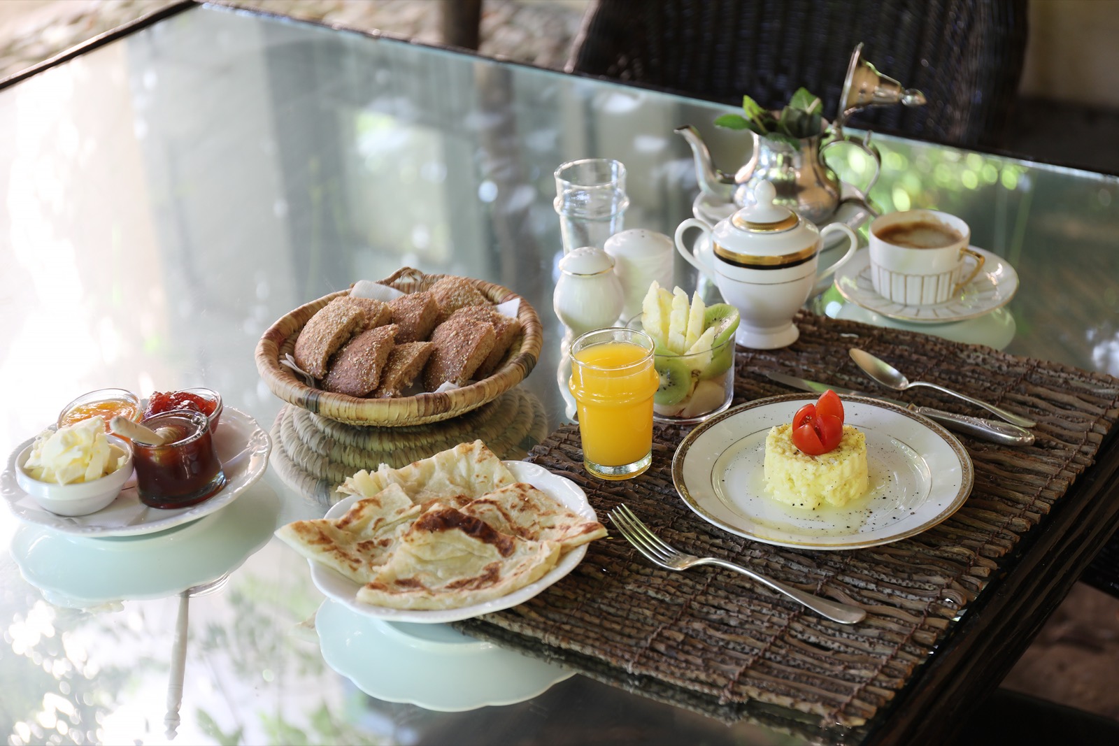 Le petit-déjeuner de la maison — msemen, pâtisseries, jus d'orange et thé dressés sur la nappe
