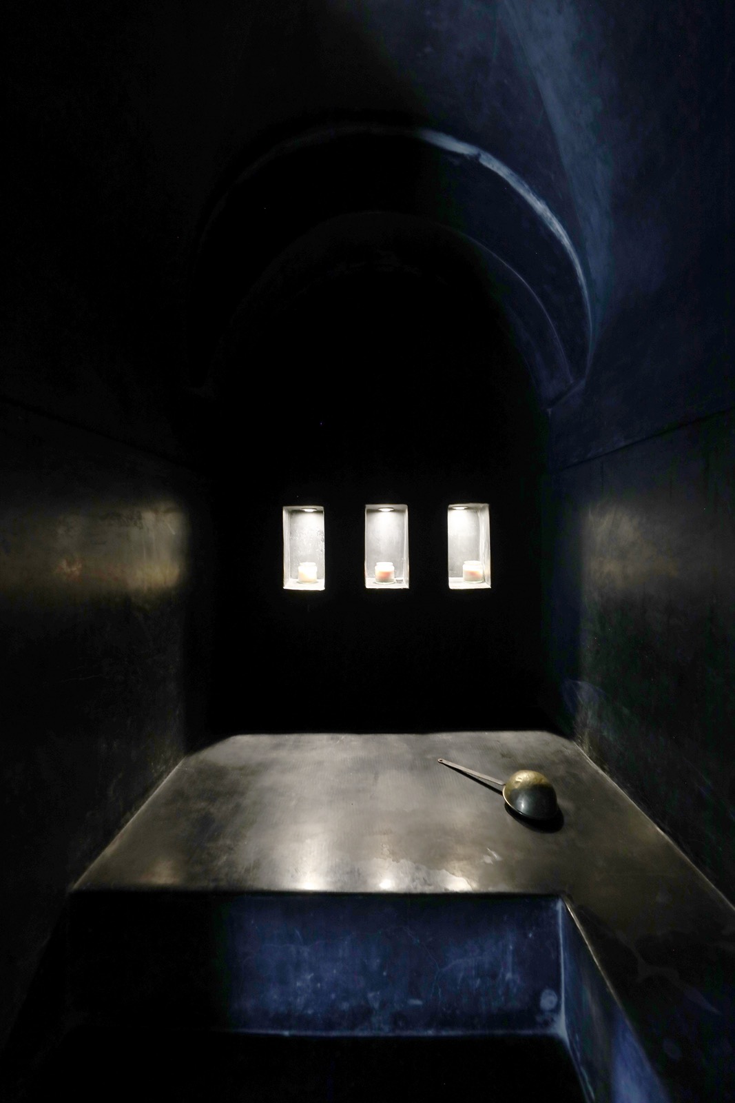 Le hammam traditionnel de la maison, sa niche voûtée en pénombre et son bassin de pierre